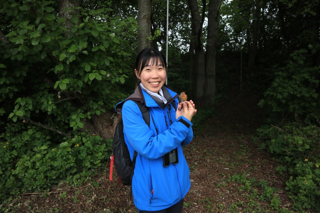 Sunny Tseng during fieldwork, holding a European Robin